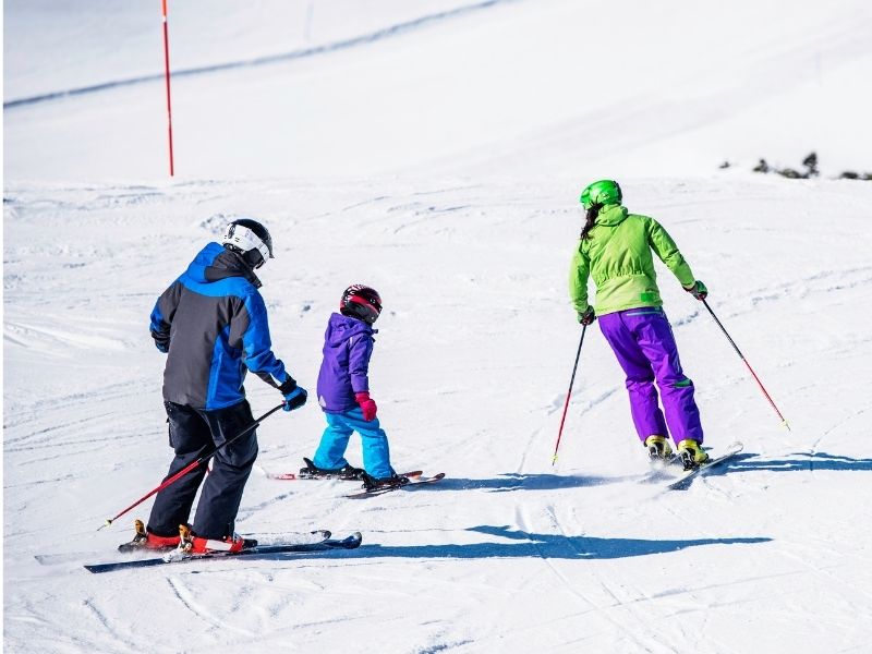 Mother, father, and child learning to ski on a ski hill in Leavenworth Washington in winter.