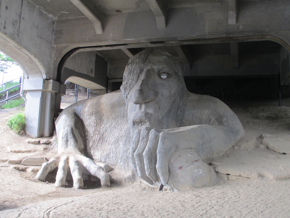 Art installation piece of a massive concrete troll crawling out from the floor underneath the bridge.