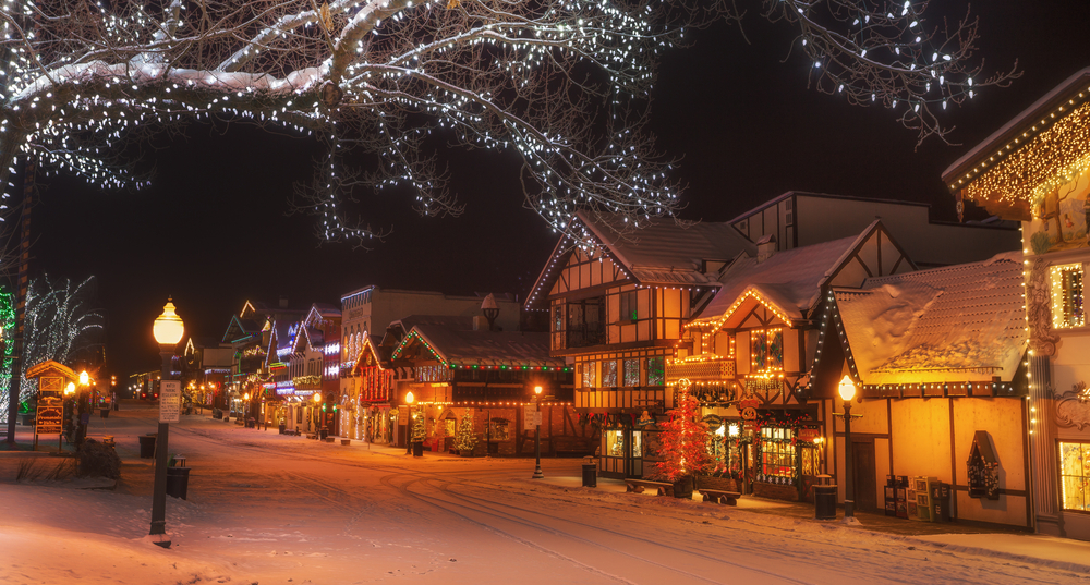 Snowy Leavenworth winter street with traditional Bavarian style architecture and Christmas lights and an orange glow to the street.