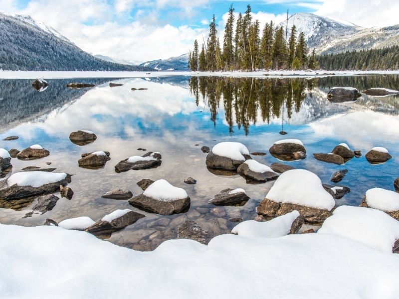 Snow-covered landscape and rocks with the lake still unfrozen in Lake Wenatchee State Park, a popular place for snow play near Leavenworth in winter