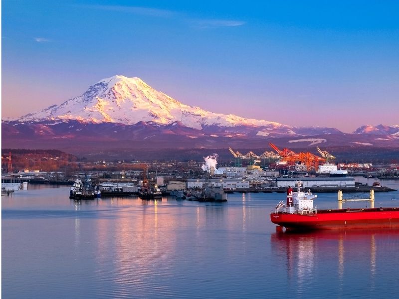 Sunset over Seattle featuring boats in Puget Sound and cranes in the distance and a snow-capped Mount Rainier, the subject of many quotes about Seattle