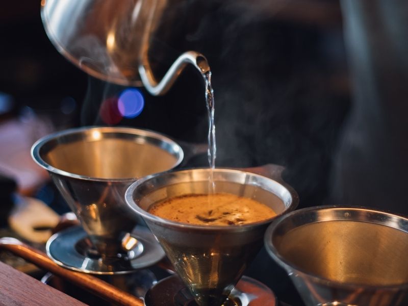 Three cups of pourover coffee being prepared at a hip third wave coffee shop.