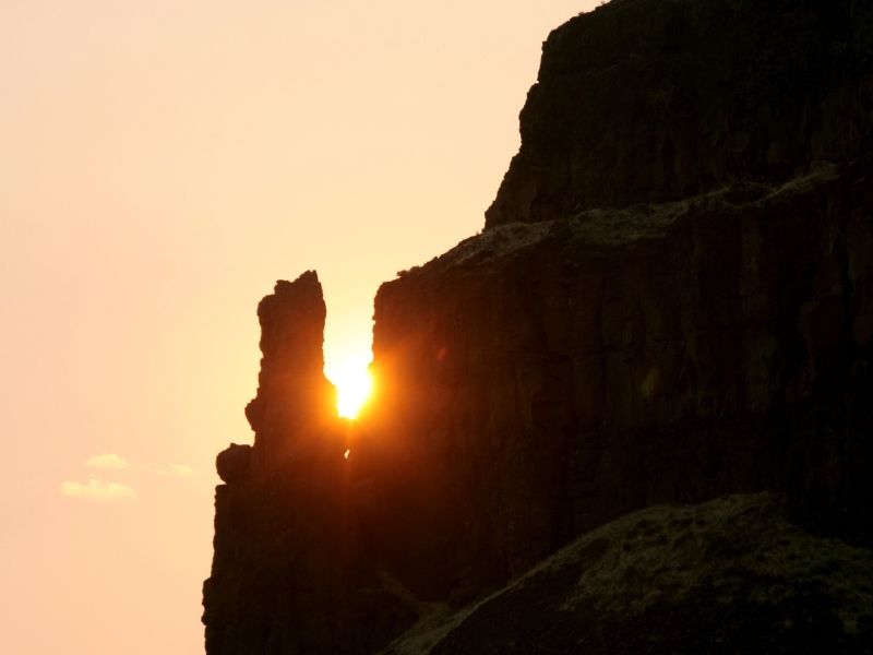 A rock crevice with the setting sun bursting behind it at sunset on this Washington winter hike.