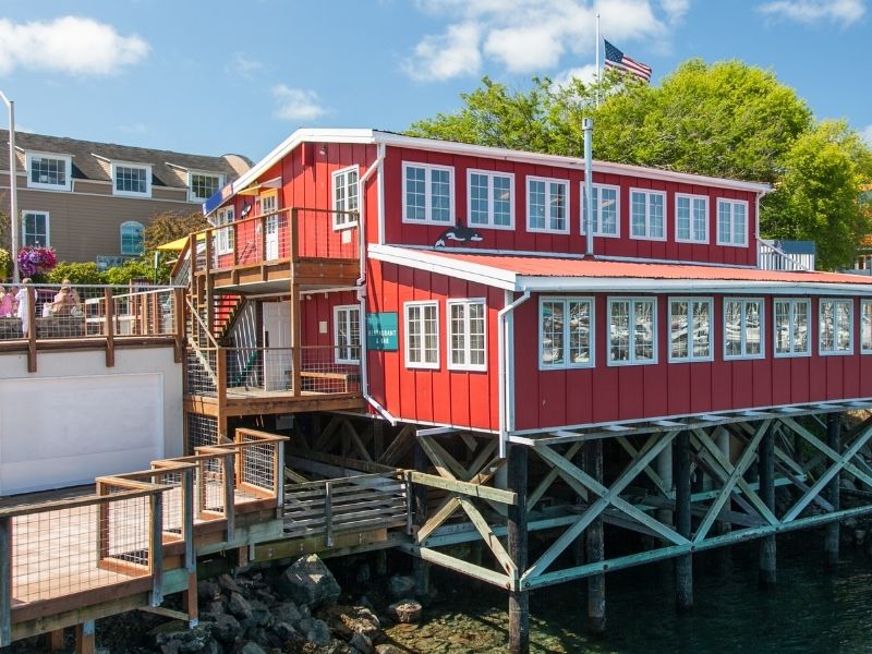 A bright red wooden building on the pier in Friday Harbor, San Juan with an American flag flying.