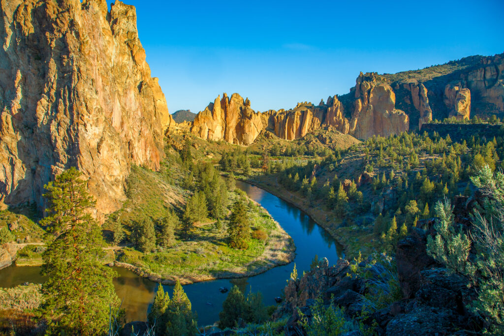 smith rock oregon with a river in the center of the photo, taken near golden hour