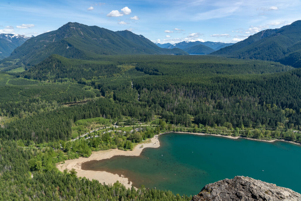 view from rattlesnake ledge, one of the best places for hiking near seattle washington. a lake is in a foreground and a forest with mountains in the background
