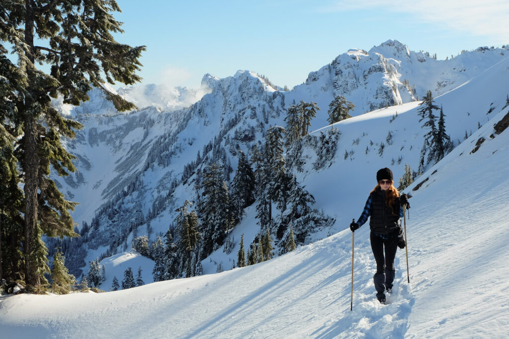 woman with 2 trekking poles hiking washington gothic basin in the snow