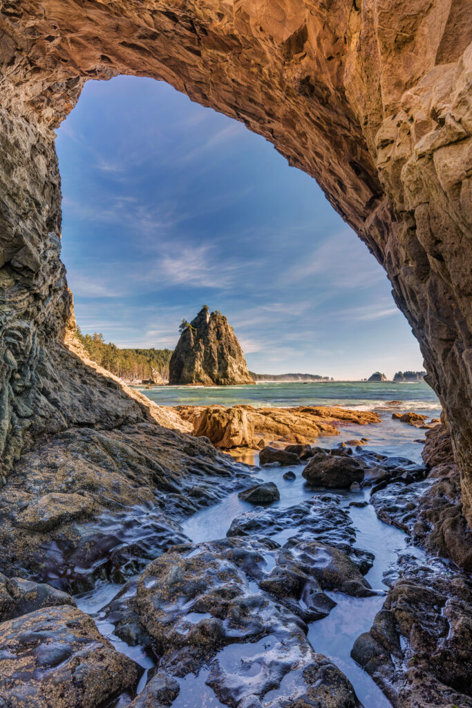 rialto beach as seen through hole in the wall on a sunny day