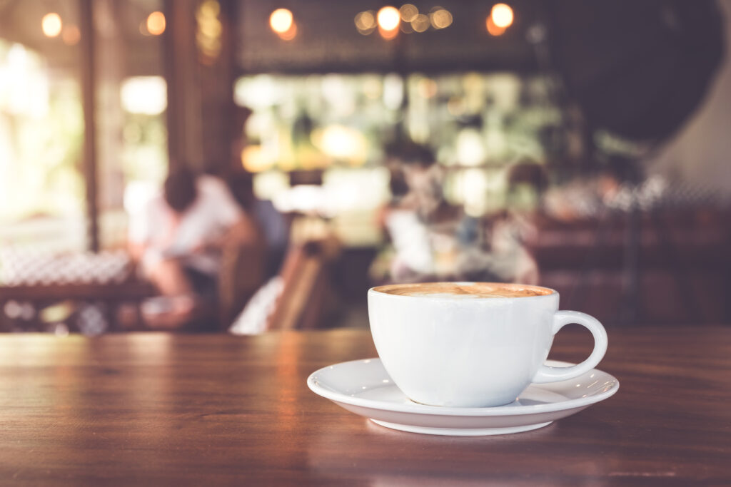 latte in a white mug sitting on a wooden table in a coffeeshop