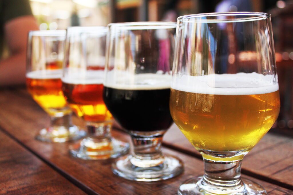 flight of 4 craft beers on a wooden table. craft beer belongs on any list of what to do in bend or