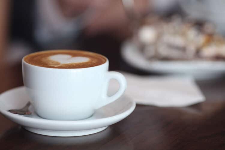 latte in a white cup with heart shaped latte art on a table at one of the best coffee shops in bend or