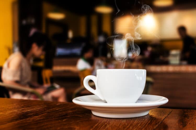 steaming white mug on a dark wood table