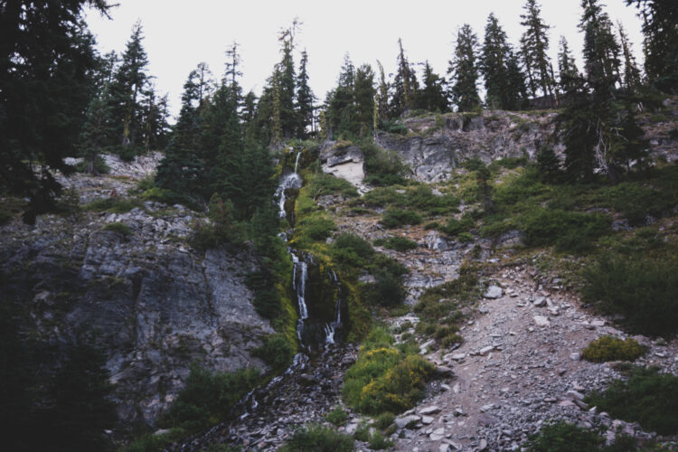 Vidae Falls, a tiny trickle of a waterfall cascading over some rocks, on an overcast day in winter in Crater Lake National Park