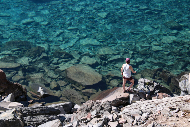 woman standing at the edge of the water of crater lake in cleetwood cove