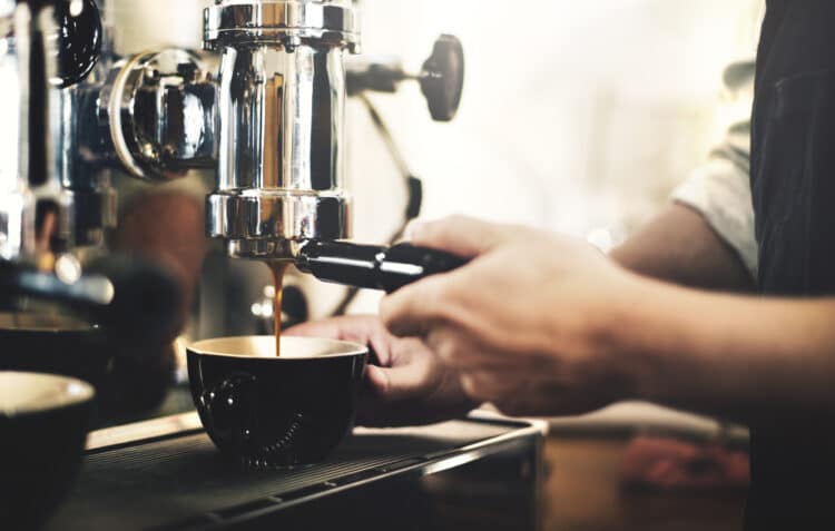 espresso being pulled into a black cup