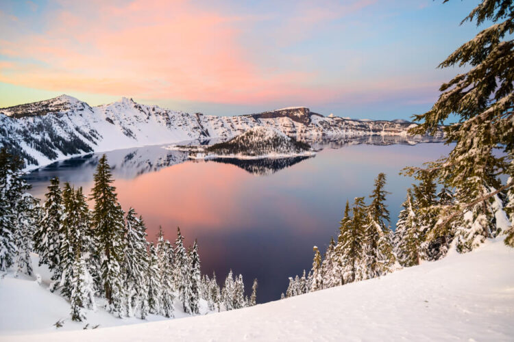 View of Crater Lake from seen from above at sunset or sunrise with pastel colors above the lake