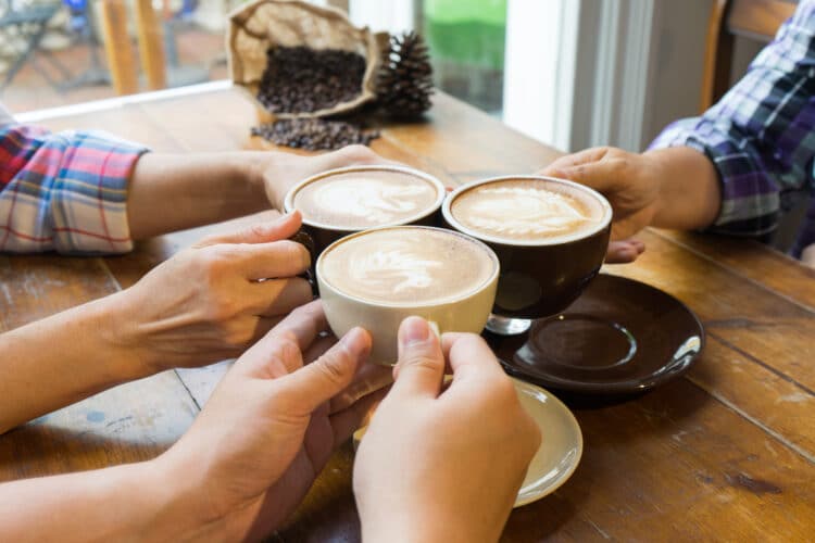 3 lattes being toasted over the table at one of the best coffee shops in bend oregon