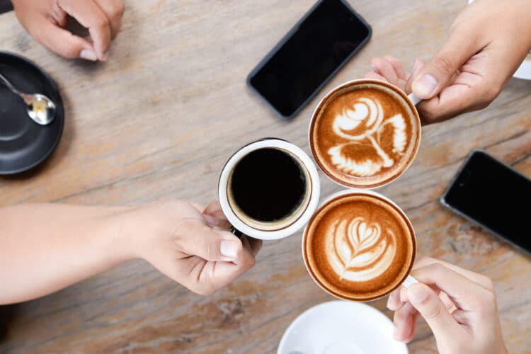 3 hands holding up coffee cups as shot from above. the best coffee in bend oregon can be found in shops like this