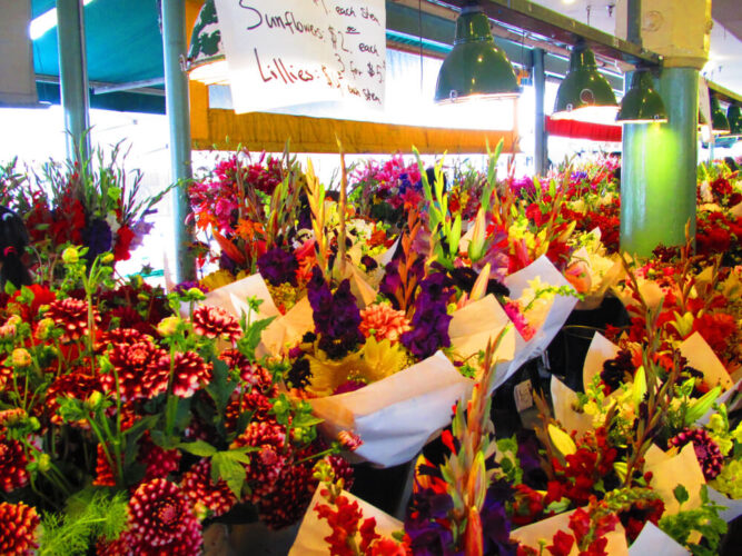 Brilliant red, purple, and green floral bouquets at a flower stall in Pike Place Market, a popular Seattle date location.