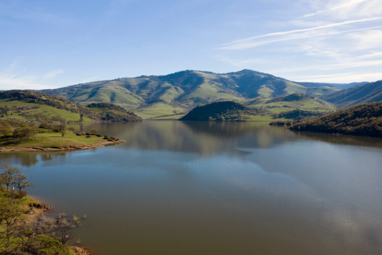 a peaceful, still lake surrounded by low mountains or hills on a clear sky day