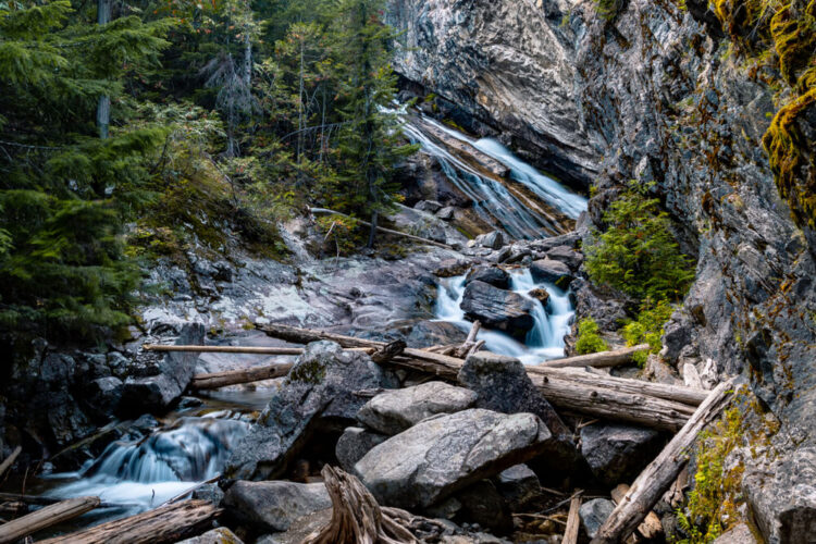 Rocks and fallen logs in a waterfall near Seattle, going through a canyon type landscape.