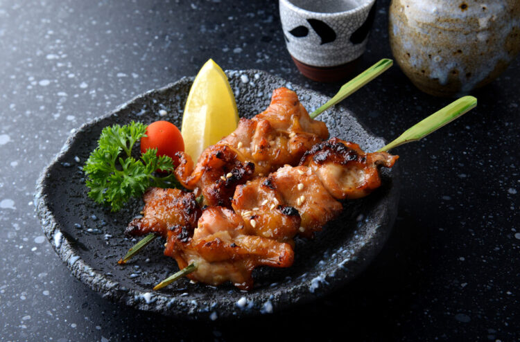 Two sticks of Japanese yakitori (grilled chicken skewers) served on a plate.