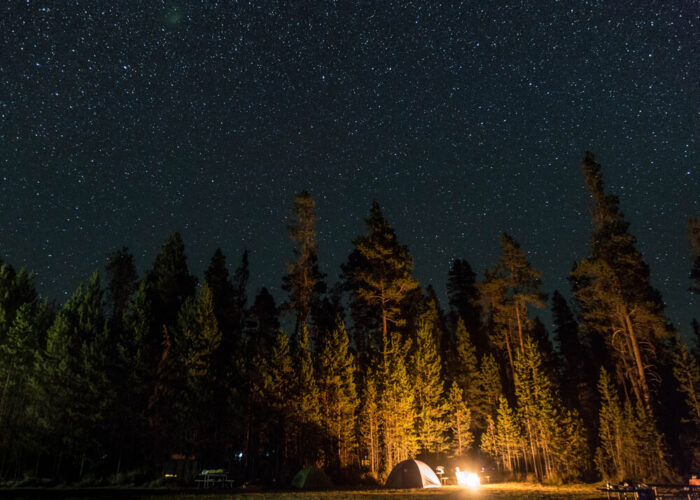 People camping in a tent with stars above them.