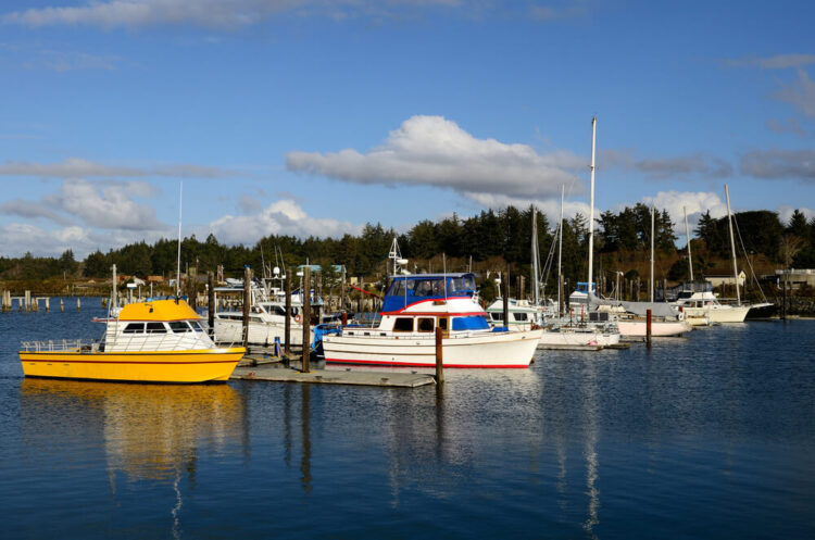 Small fishing boats parked in the Coquille River marina, in Bandon Oregon, white and yellow boats in the marina
