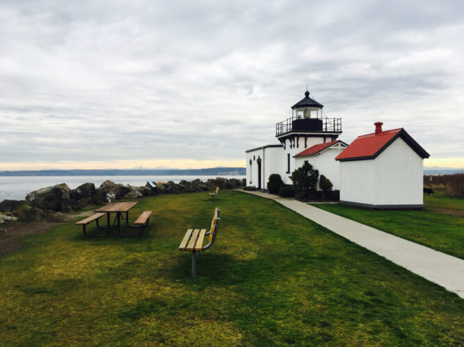 Hansville lighthouse with ocean and grass background. Picnic table and bench offering views over the Puget Sound from this beautiful coastal town in Washington state.