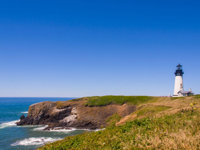 the coastal rugged landscape of the oregonc oast with a white lighthouse and lighthouse keeper house on the edge of the pacific ocean