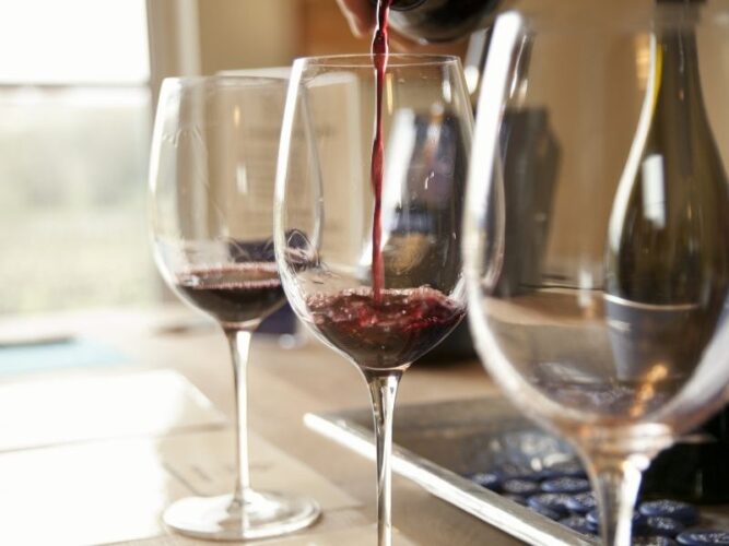 row of three wine glasses being filled with tastes of red wine from oregon