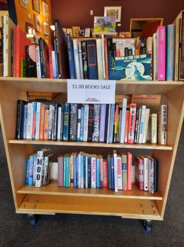 sign that reads $1 used books sale with a shelf of books