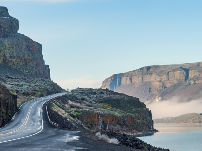 Driving on the edge of a lake or river along the Coulee Corridor while on a washington state road trip