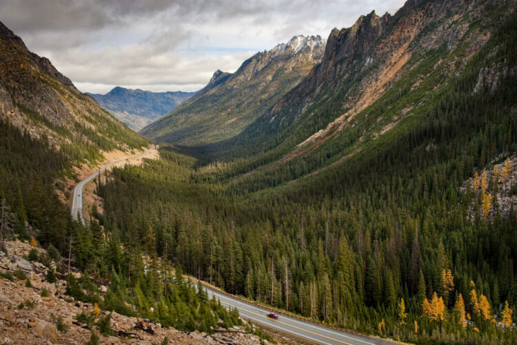 One lone red car on a highway road tripping in Washington in the North Cascades