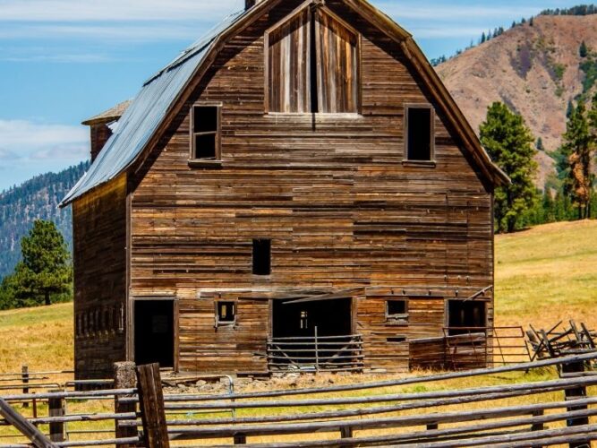 a small barn in the cle elum area of washington with a yellow-grassy field and fence