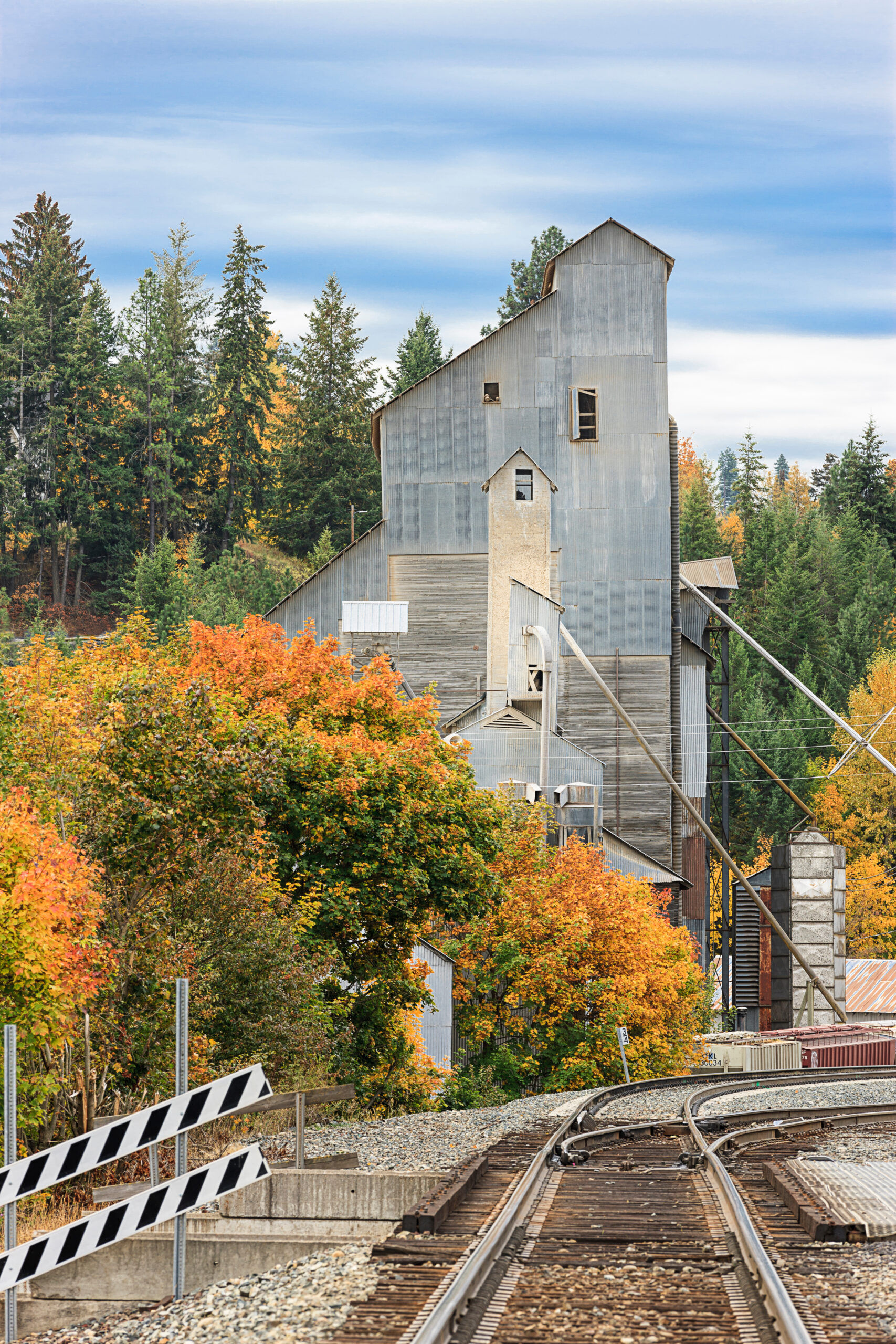 a cute barn-like structure in the small town of bonners ferry idaho, with a railroad track and orange fall foliage