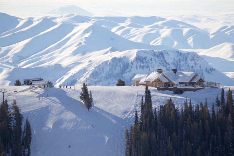 the small town of sun valley idaho blanketed in snow in the middle of winter, with a ski resort and lots of evergreen trees next to a ski run