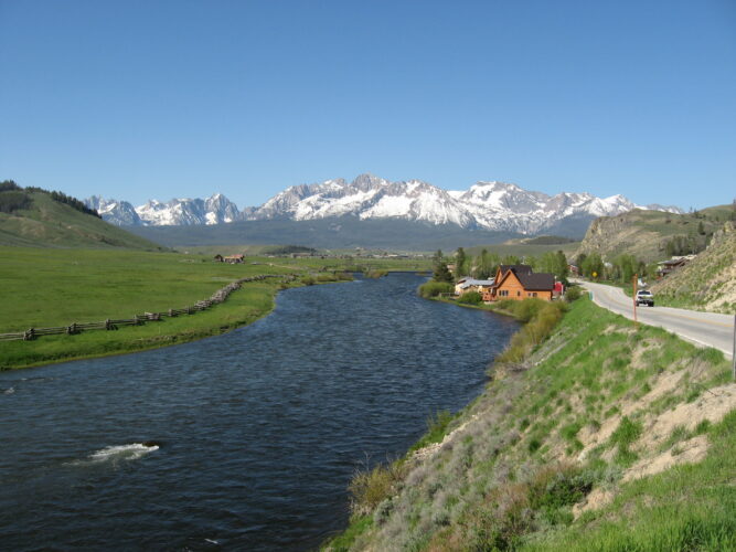 a small town on the banks of the salmon river in charming little stanley, a beautiful idaho small town, with snow on mountains in the distance.