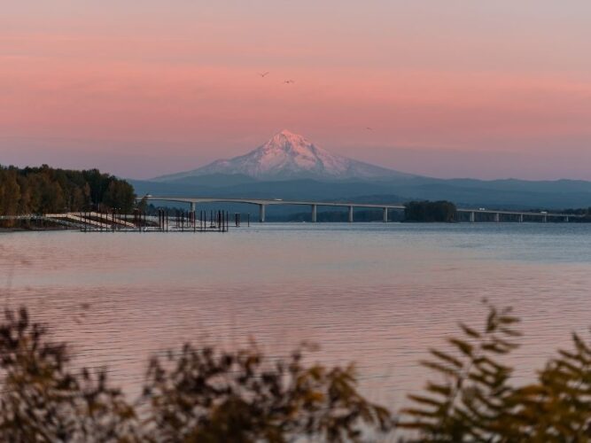 the small town of vancouver washington with mt hood in the background at sunset wtih a bridge spanning the columbia river